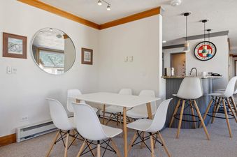 The dining area at The Charter L222 showcasing a white dining table with six chairs and an adjacent bar with bar stools.