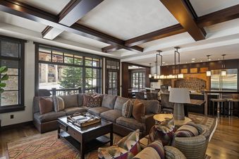 A large, inviting living room at Skiside Retreat at Flagstaff Lodge with comfortable seating, a coffee table, and an adjacent kitchen area.