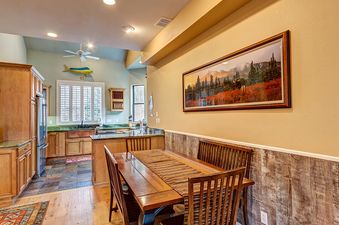 A dining room with a wooden table, chairs, and a runner on the table.