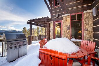The patio of 492 Golf Course Circle with the grill covered in snow on a sunny winter day.