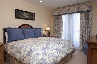 Cozy bedroom in Countryside 183 with elegant blue and white floral bedding and matching curtains.