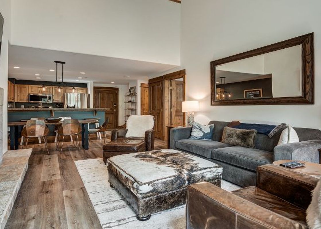A cozy, rustic-chic living room with a fireplace and an open-concept kitchen and dining area.