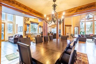 The dining area at 213 County Road 1041 features a large wooden table and chairs, illuminated by a grand chandelier.