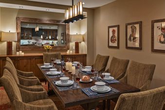 A formal dining room in Capitol Peak One Steamboat Place 608 features a long wooden table set with dinnerware, surrounded by upholstered chairs.