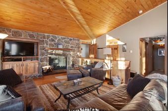 The inviting living area features comfortable seating, a stone fireplace, and a flat-screen TV.