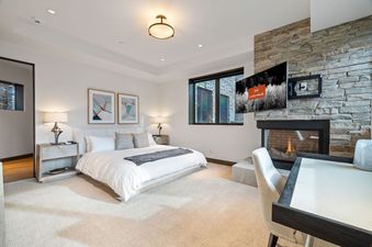 A cozy bedroom with a large bed, fireplace, and flat-screen TV.