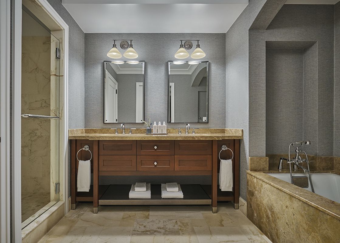 The primary bathroom features a double vanity with two sinks, two mirrors, a walk-in shower with a glass door, and a bathtub.