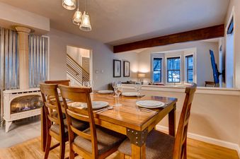 The dining area and part of the living room at High Street Retreat, featuring a wooden dining table set for guests and a fireplace.