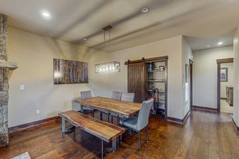The dining area in Keystone Townhome features a large wooden table and bench, with a modern chandelier overhead.