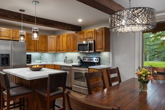 A modern kitchen and dining area in Top of the Village Trails 101 with wood cabinetry and view of a grassy lawn outside.