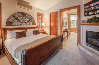 A bedroom with a large bed, a fireplace, and a flat screen TV