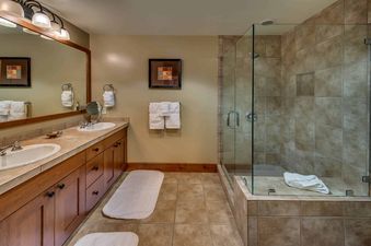 A bathroom with a walk-in shower and dual sinks.