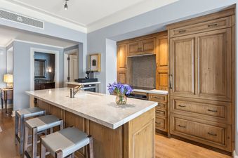A modern kitchen with a large light-colored island and light wood cabinetry.