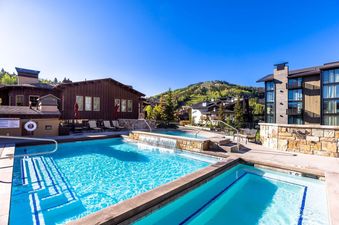 Outdoor swimming pools and hot tubs at The Chateaux Deluxe One Bedroom with mountain views.