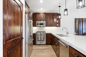Modern kitchen with dark wood cabinets, stainless steel appliances, and quartz countertops.