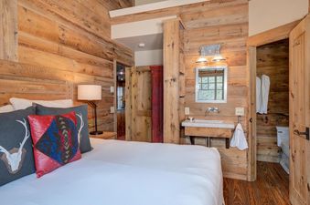 Moonlight Basin 9 Cabin Hollow bedroom with a white, king-size bed and rustic wood walls.