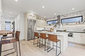 A kitchen with white cabinets and a large island with seating.
