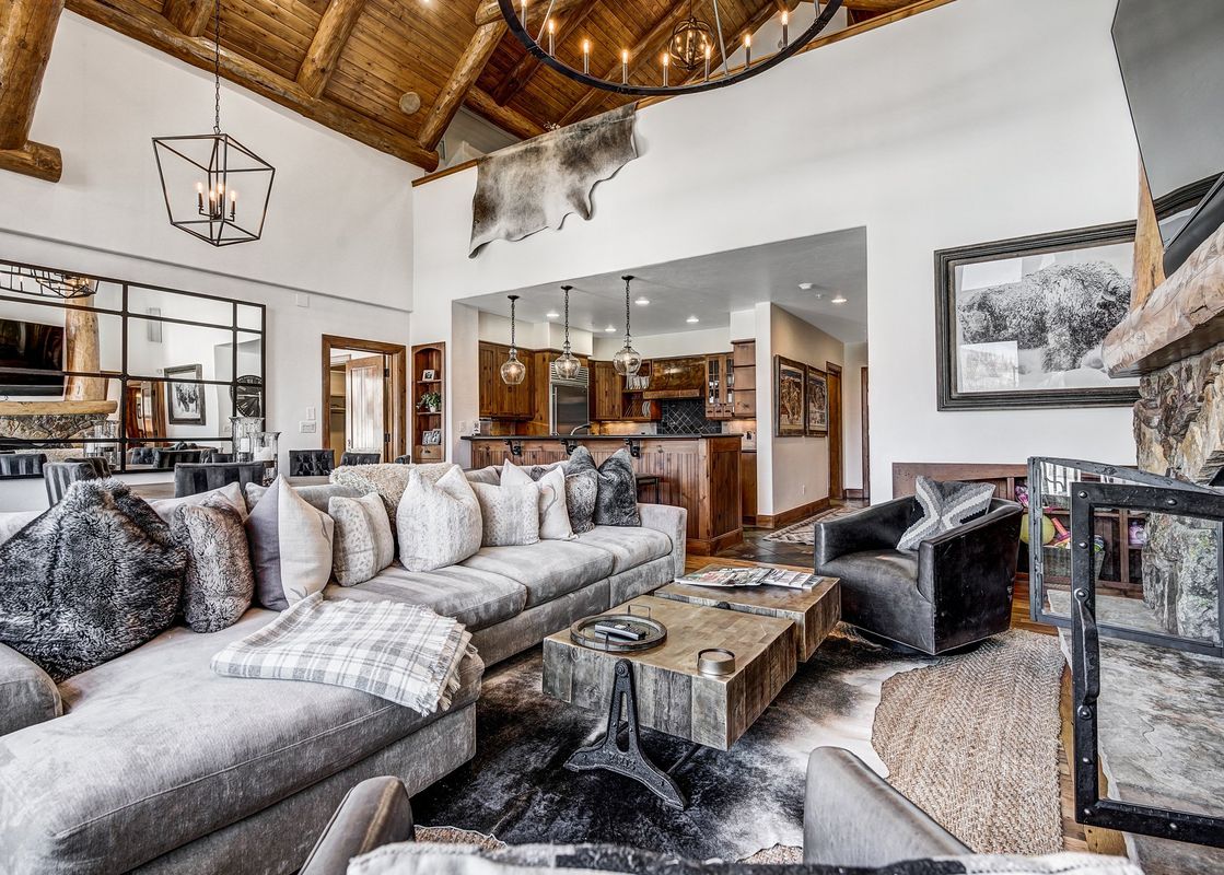 A spacious and inviting living area in Bear Paw Lodge 4 Bedroom Plus Loft, featuring a large gray sectional sofa, a rustic coffee table, and a grand fireplace.