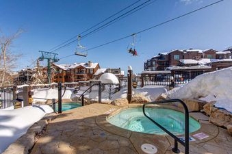 Relax in the hot tub after a day on the slopes at Silver Summit, surrounded by snow-covered mountains.