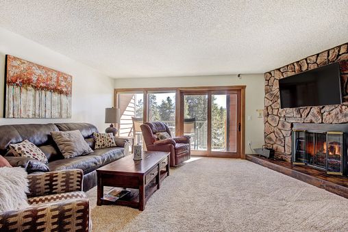 Living room with a fireplace, a couch, a chair, a coffee table, and a view of the mountains.