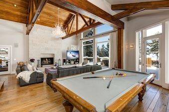 The spacious living area of Blackstone 13th Green features a cozy fireplace, comfortable couches, and a pool table.