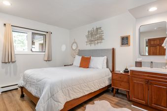 A cozy bedroom with a comfortable bed, nightstands, and an attached vanity area with a mirror.