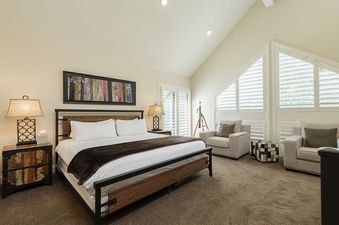 The bedroom at Deer Valley Daystar 1793 features a large bed, two armchairs, and ample natural light.
