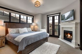 A bedroom with a king-size bed, a fireplace, and a view of the mountains.
