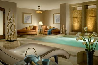 A luxurious and tranquil indoor spa area in the Arrabelle 1 Bedroom with a glowing hot tub and comfortable chaise lounges.