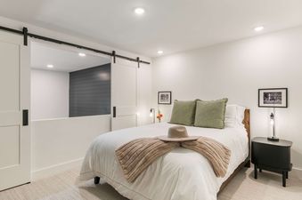 Cozy bedroom in the Solstice Suite with a queen bed and sliding barn doors.