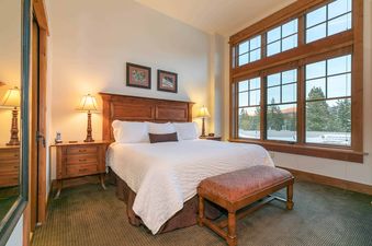 A bedroom with a large window offering views of a snowy mountain range.