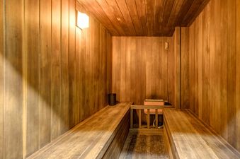 The image shows the private sauna at Copperbottom Inn 202, featuring warm wooden interiors, benches, and a heater.