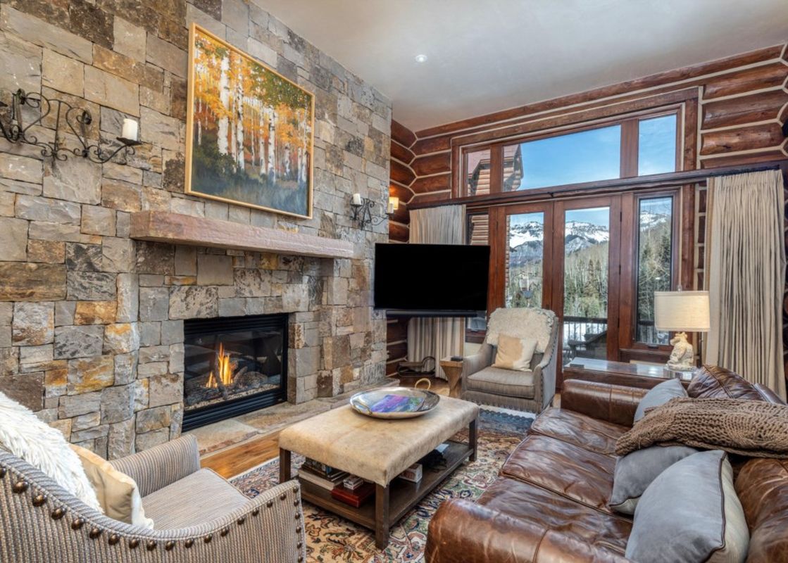 The living area in Townhomes on the Creek 139 features a stone fireplace and views of the mountains.