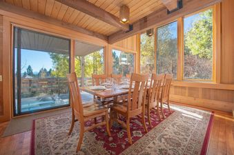 The dining area at Barry House featuring a wooden table, six chairs, and large windows with autumn views.