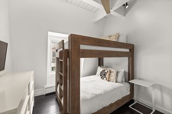 A bunk bedroom at Chateau Dumont Unit 21 with a wooden bunk bed, white bedding, and a dresser with a television.