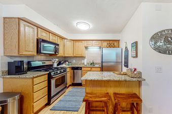 The kitchen at Emerald Pines at Motherlode C, featuring a modern kitchen design, a sleek stainless-steel refrigerator, and a kitchen island with seating.
