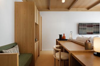 A modern bedroom at Mollie Aspen Mountain King featuring light wood accents, a green bench, a built-in desk, and a comfortable bed.