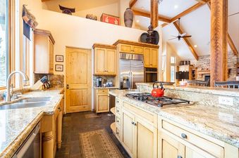 The kitchen at 213 County Road 1041 features light wood cabinetry, granite countertops, and a modern stainless steel refrigerator.