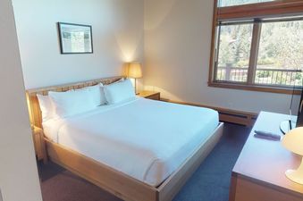 Manor Vail 370 bedroom has a king size bed, wood floors, and a window with a view of the trees.
