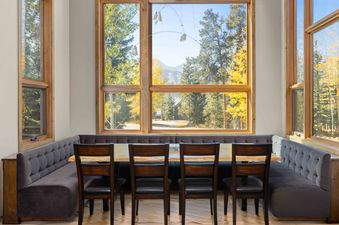 A dining room with a large window that offers a view of a mountain and fall foliage.