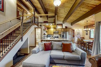 The living area of Phoenix 122 is designed for relaxation, featuring a comfortable sectional sofa with throw pillows and a ceiling with exposed wooden beams.