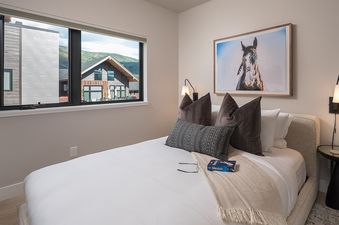 A serene bedroom at Canton House with a comfortable bed, stylish decor, and a window offering views of buildings and mountains.