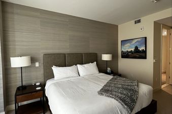 Modern bedroom in the Lift 4 Bedroom Suite featuring a king bed with white bedding, nightstands, and textured accent wall.