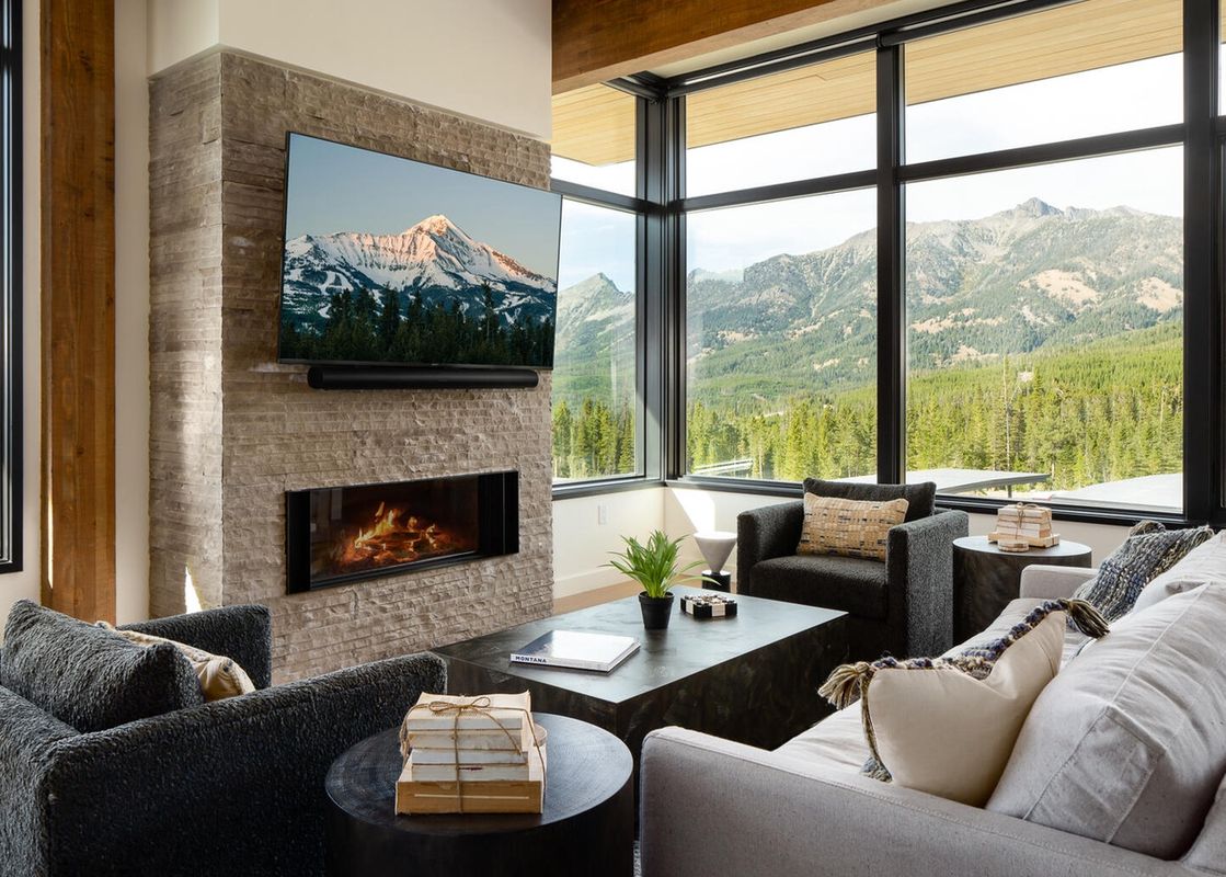 The living room of Moonlight Basin 201 Lakelodge has a fireplace with a view of the mountains outside.
