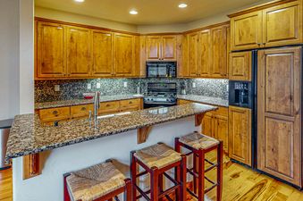 The kitchen in EagleRidge Townhomes 1512 features wood cabinets, stainless steel appliances, and a granite countertop.