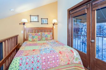 Charming bedroom in Manitou Lodge 6 with a cozy quilt and balcony access.