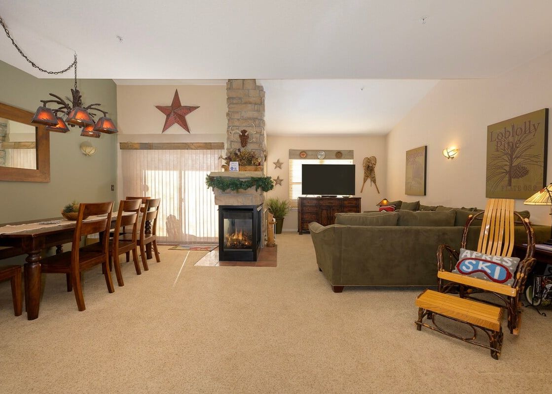 The living room at Waterside West E206 features a fireplace, a long sofa, a comfortable armchair, and a dining area.
