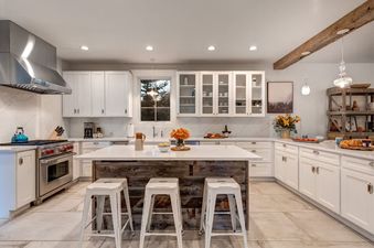 Luxurious kitchen at Palomino Ridge featuring white cabinetry, marble countertops, a rustic wood island with barstools, and high-end stainless steel appliances.