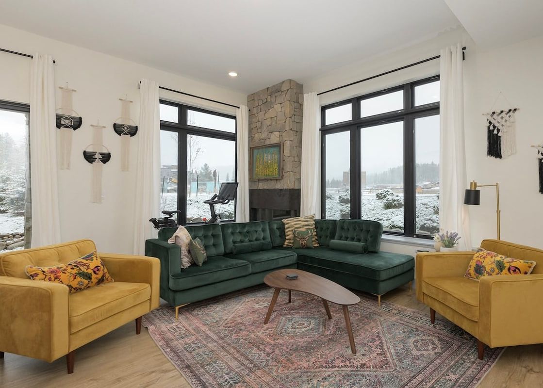 A luxurious living room at Timber Fox B 2102 featuring a plush green sectional sofa, two mustard yellow armchairs, and a modern wooden coffee table, all set on an ornate patterned rug.