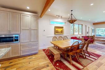 Dining area in Eagles Rest 5 featuring a large wooden table and chairs on a red rug.